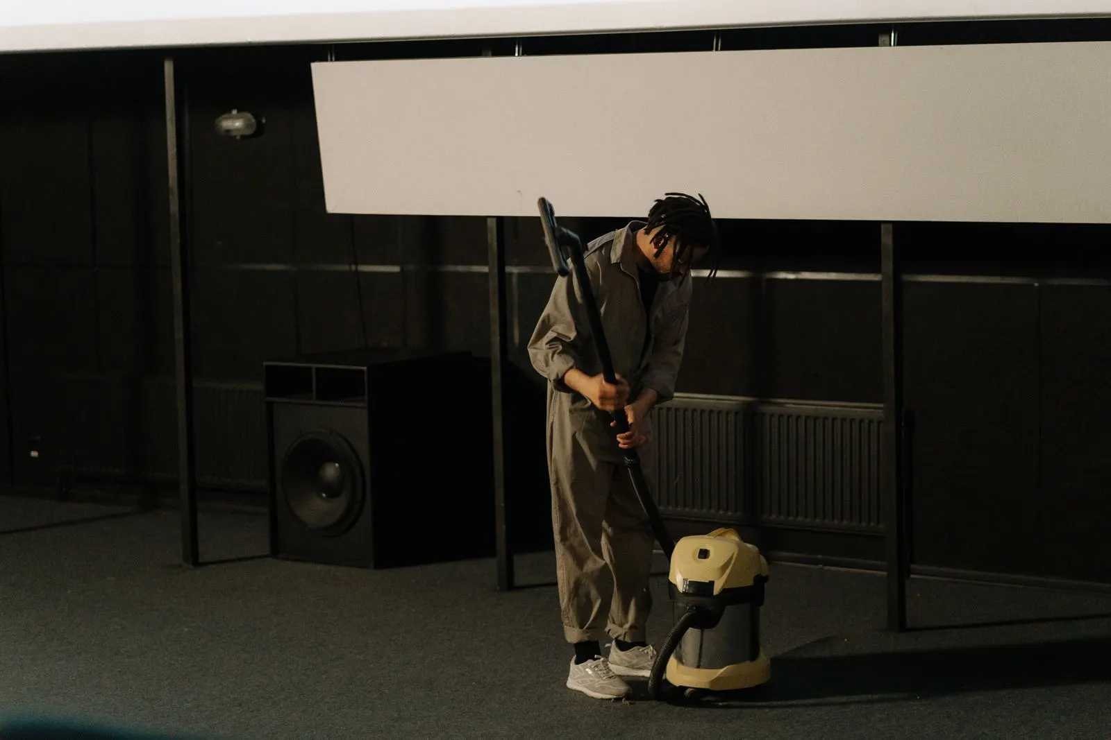 Worker vacuuming a large carpeted room with a commercial vacuum