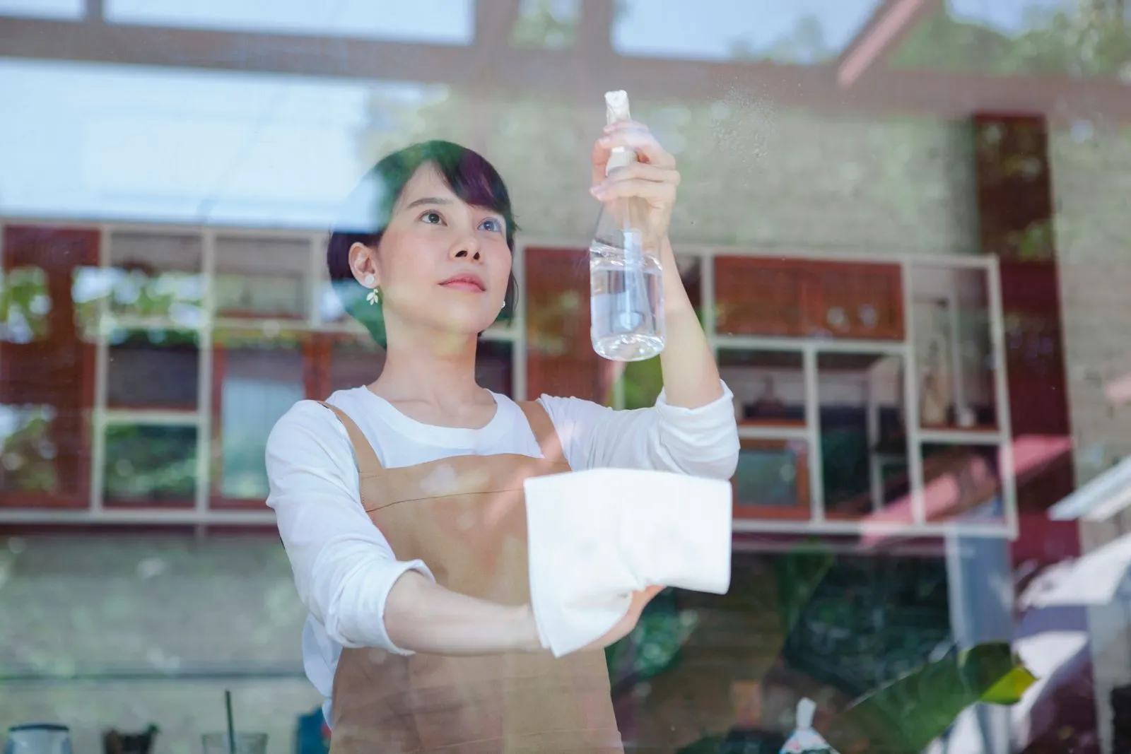 Cleaner spraying and wiping a glass window